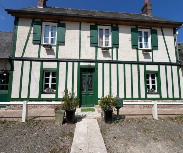 Façade rénovée avec colombages peints en vert et enduit clair
