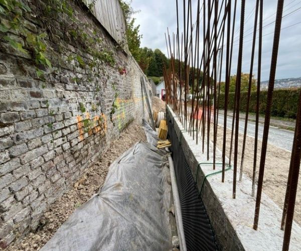 mur en pierre existant et nouveau mur béton armé en construction