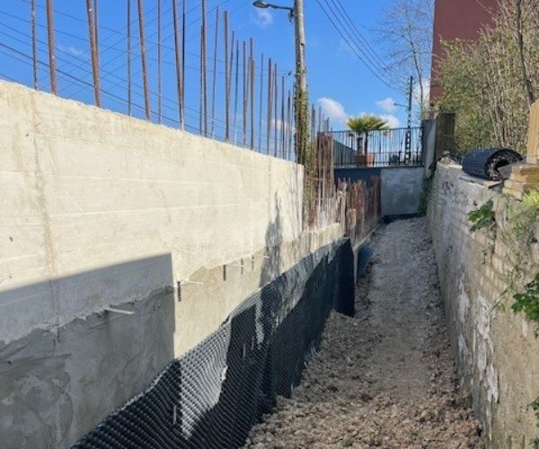 Étanchéité et drainage d'un mur en béton armé sur un chantier à Rouen.